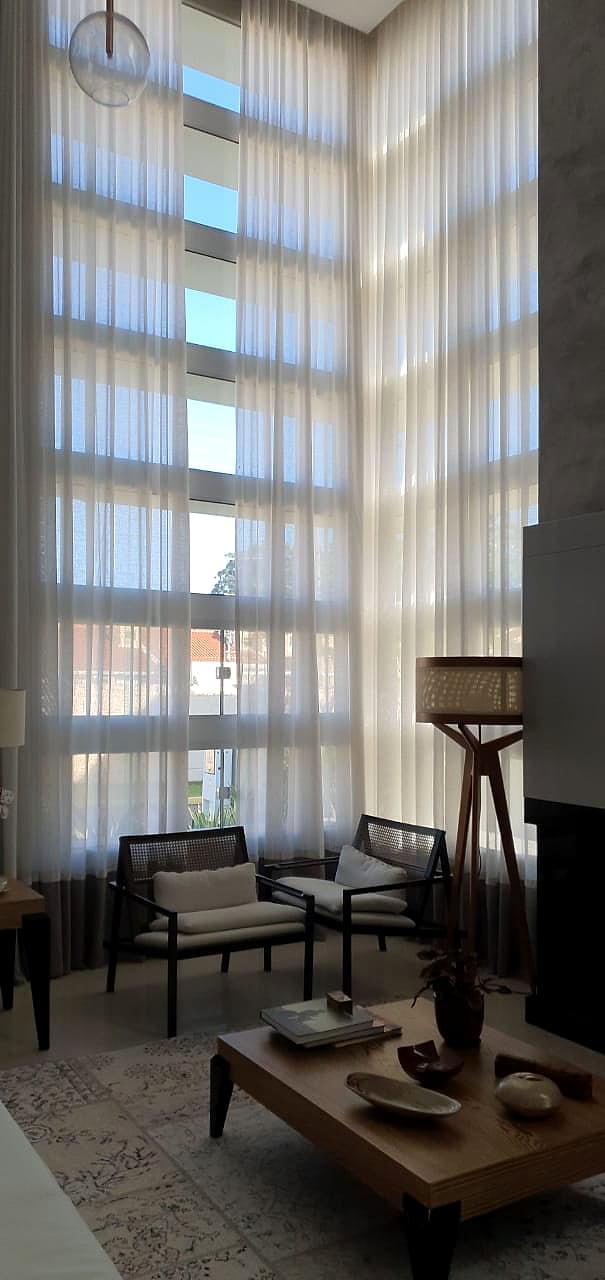 Sala de pé-direito duplo com cortina wave em voil branco